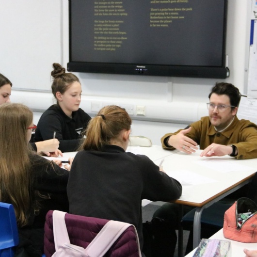  students writing poetry at a workshop led by a poet in school